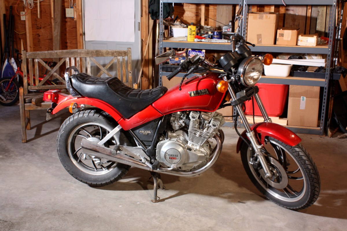 A red motorcycle displayed inside a practical workshop space.