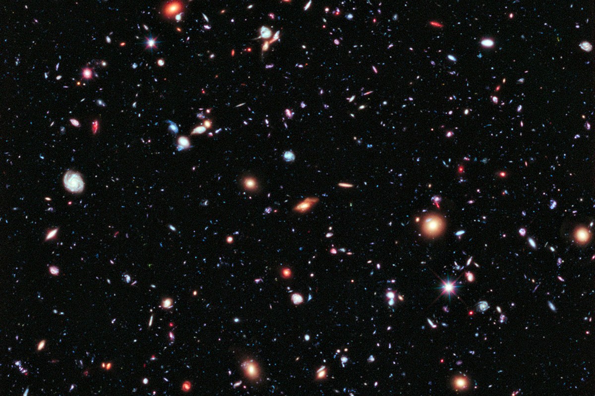 A dense field of stars and distant galaxies across a dark sky.